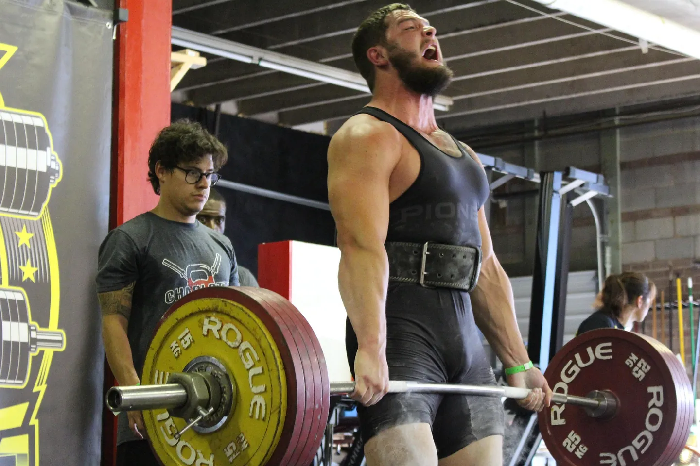 Lifters training near a squat rack in a busy gym