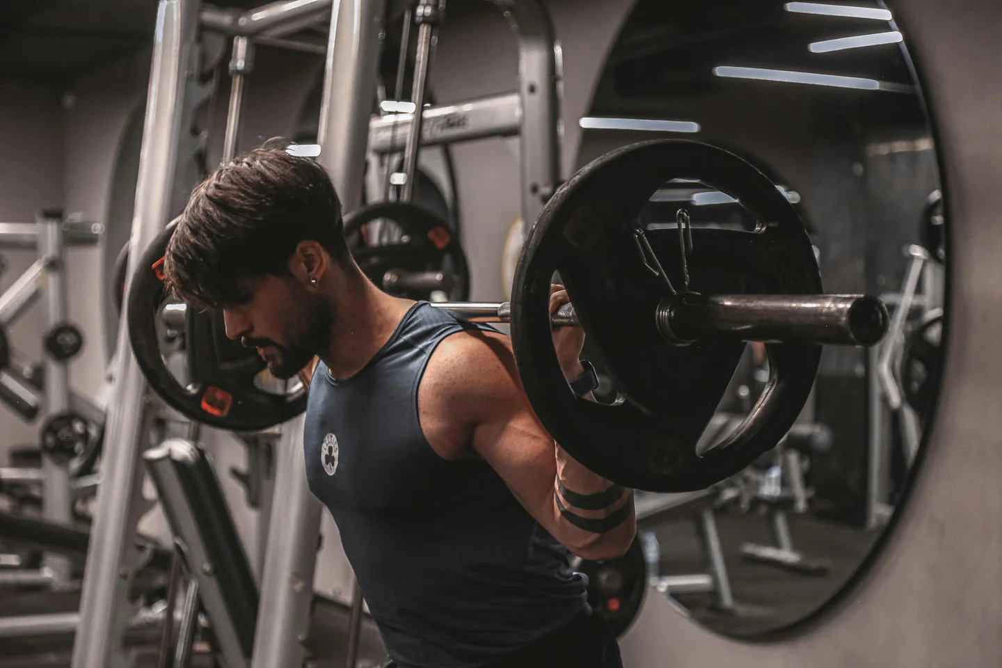A lifter in a blue vest unracking a barbell for a squat