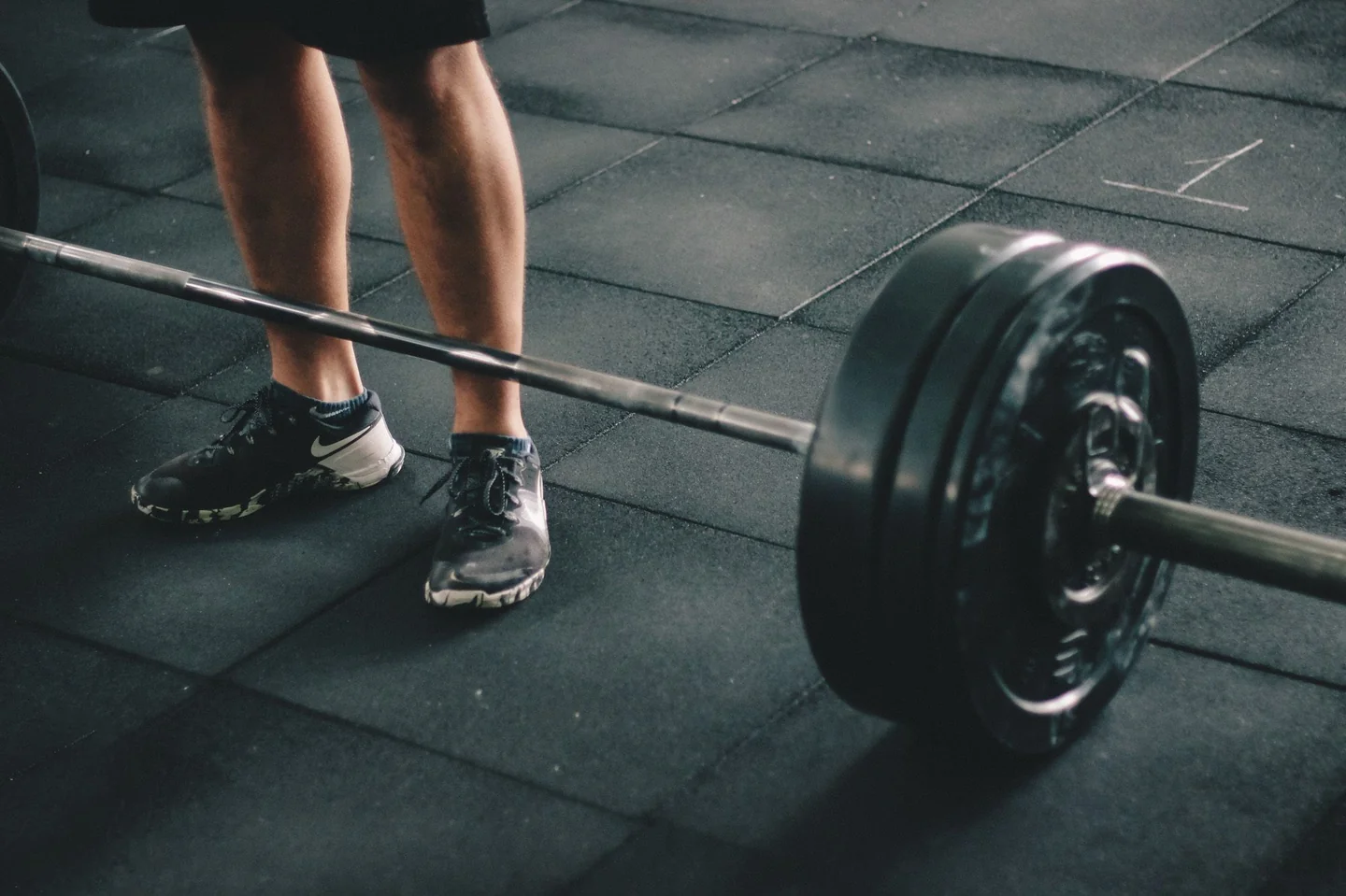 A lifter's feet standing over a loaded barbell, ready to pull